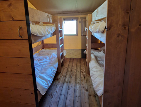 Slaapkamer met houten stapelbedden en witte dekens in een Safari tent bij Mooirust, Nederland.