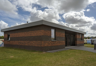 Modern bakstenen gebouw bij Camping Jagtveld vakantiepark in Zuid-Holland, Nederland, met bewolkte lucht.