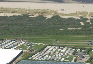 Luftaufnahme von Camping Jagtveld in Südholland, Niederlande, mit Wohnwagen bei Strand und Dünen.
