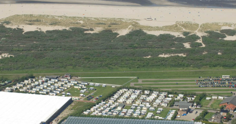 Vista aérea de Camping Jagtveld en Zuid-Holland, Países Bajos, con caravanas cerca de la playa y dunas.