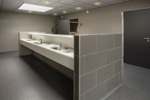Baño comunitario moderno con varios lavabos y paredes de azulejos en Camping Jagtveld, Holanda Meridional.