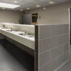 Baño comunitario moderno con varios lavabos y paredes de azulejos en Camping Jagtveld, Holanda Meridional.