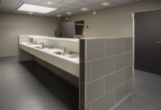 Baño comunitario moderno con varios lavabos y paredes de azulejos en Camping Jagtveld, Holanda Meridional.