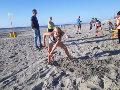 Niños y adultos cavando y jugando en la arena en la playa del Camping Jagtveld en Holanda Meridional, Países Bajos.