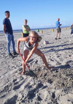Niños y adultos cavando y jugando en la arena en la playa del Camping Jagtveld en Holanda Meridional, Países Bajos.