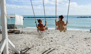 Dos personas columpiándose en una playa cerca de 's-Gravenzande, Holanda Meridional, junto al mar.