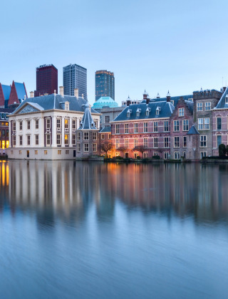 Vista nocturna de edificios históricos y agua en La Haya, Holanda del Sur, Países Bajos, con el skyline urbano.