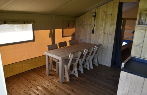 Binnenkant van een safaritent bij Mooirust in Nederland met houten vloer, eettafel en stoelen.