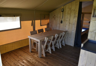 Binnenkant van een safaritent bij Mooirust in Nederland met houten vloer, eettafel en stoelen.