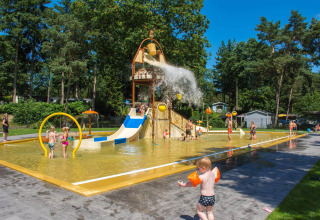 Kinderen spelen in een kleurrijke waterspeeltuin met glijbaan en waterton bij Camping Samoza, Gelderland.