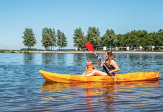 Moeder en kind genieten van kajakken op het meer bij vakantiepark Bad Hoophuizen in Gelderland, Nederland.