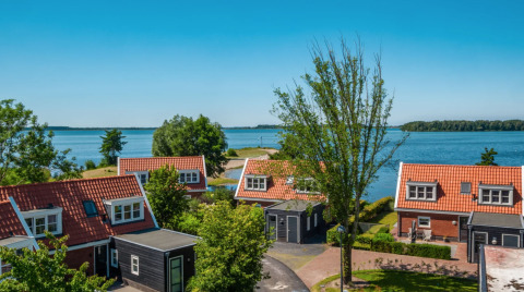 Vakantiehuisjes met rode daken aan het water in vakantiepark Bad Hoophuizen, Gelderland, Nederland.