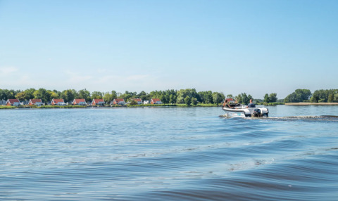 Zicht op vakantiehuisjes met rode daken langs het water in Bad Hoophuizen, Gelderland, Nederland.