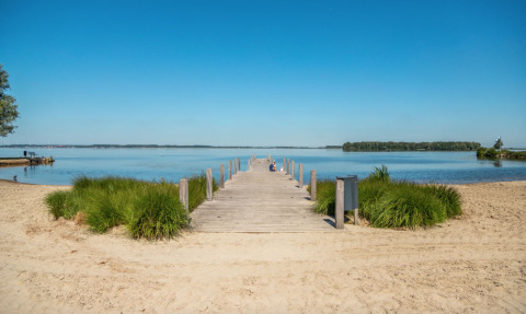 Houten steiger aan het water met zandstrand en gras, in de buurt van Hulshorst, Gelderland, Nederland.