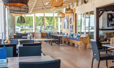Gezellige eetruimte in een modern restaurant bij vakantiepark Bad Hoophuizen in Gelderland, Nederland.