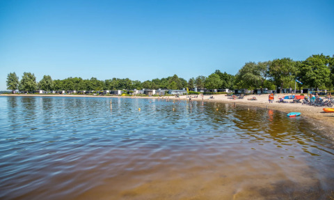 Zicht op het strand en het water bij vakantiepark Bad Hoophuizen in Gelderland, Nederland op een zonnige dag.