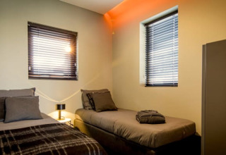 Chambre moderne de la lodge Modus à Bad Hoophuizen, Pays-Bas, avec deux lits simples et des fenêtres.