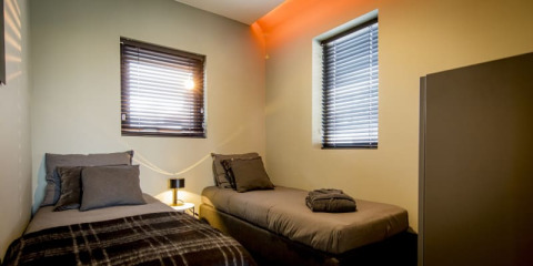 Habitación moderna en la casa Modus de Bad Hoophuizen, Países Bajos, con dos camas individuales y ventanas.
