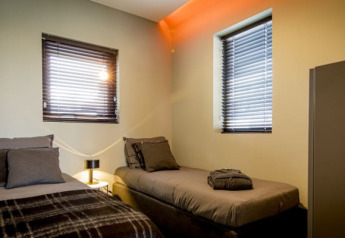 Moderne lodgeværelse på Modus i Bad Hoophuizen, Holland, med to enkeltsenge, vinduer og natbord.