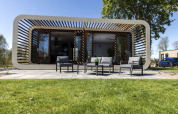 Modern Modus lodge at Bad Hoophuizen, Netherlands, featuring a patio with outdoor seating and green lawn.