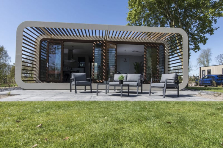 Modern Modus lodge at Bad Hoophuizen, Netherlands, featuring a patio with outdoor seating and green lawn.