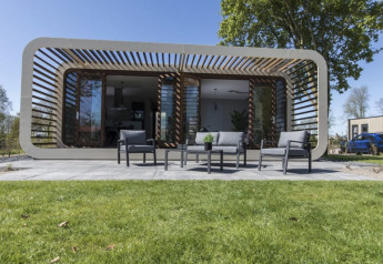Moderne Modus lodge bij Bad Hoophuizen in Nederland, met terras, zitplaats en een groen gazon ervoor.