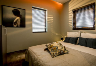 Chambre douillette à Modus, Bad Hoophuizen, Pays-Bas, avec lit double et lumière du soleil sur les murs.