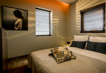 Gezellige slaapkamer bij Modus, Bad Hoophuizen, Nederland, met tweepersoonsbed en zonlicht op de muur.