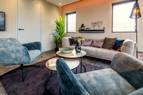 Salon moderne avec fauteuils bleus et canapé élégant au lodge Modus à Bad Hoophuizen, Pays-Bas.