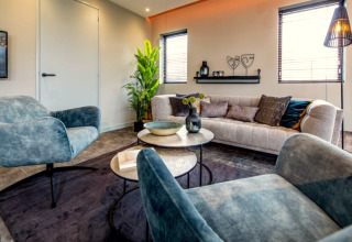 Salon moderne avec fauteuils bleus et canapé élégant au lodge Modus à Bad Hoophuizen, Pays-Bas.
