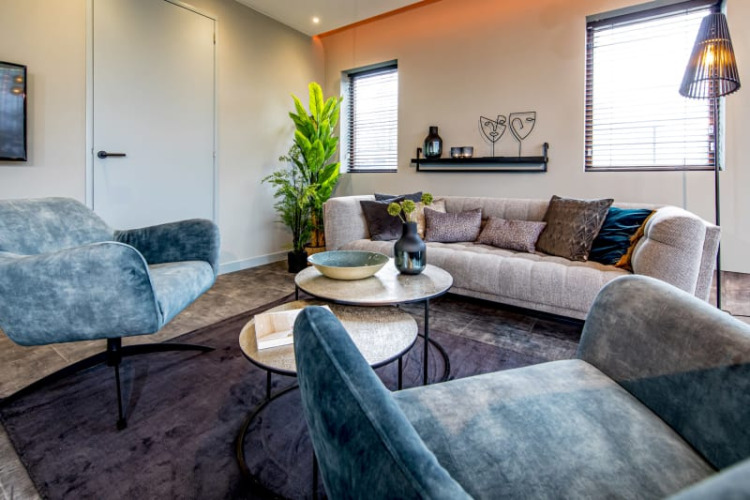 Modern living room with blue armchairs and a cozy sofa at Modus lodge in Bad Hoophuizen, Netherlands.