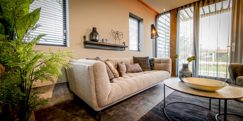 Salón moderno de una cabaña Modus en Bad Hoophuizen, Países Bajos, con gran ventanal y decoración elegante.