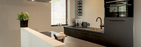 Cocina moderna en la cabaña Modus en Bad Hoophuizen, Países Bajos, con muebles oscuros y horno.