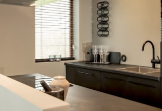 Cocina moderna en la cabaña Modus en Bad Hoophuizen, Países Bajos, con muebles oscuros y horno.