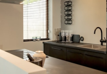 Cocina moderna en la cabaña Modus en Bad Hoophuizen, Países Bajos, con muebles oscuros y horno.