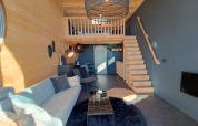 Interior of Tiny House at Bad Hoophuizen, Netherlands, with loft, modern furniture, and wood details.