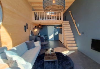 Interieur van Tiny House in Bad Hoophuizen, Nederlanden, met moderne meubels, houten accenten en een mezzanine.