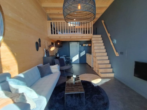 Interieur van Tiny House in Bad Hoophuizen, Nederlanden, met moderne meubels, houten accenten en een mezzanine.