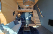 Interieur van Tiny House in Bad Hoophuizen, Nederlanden, met moderne meubels, houten accenten en een mezzanine.