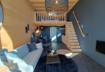 Interieur van Tiny House in Bad Hoophuizen, Nederlanden, met moderne meubels, houten accenten en een mezzanine.