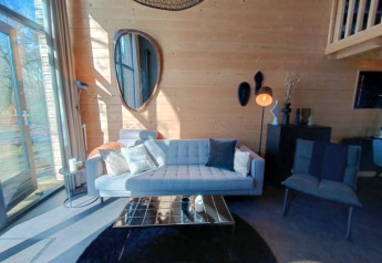 Gezellige woonkamer in Tiny House bij Bad Hoophuizen, Nederland, met houten muren en grote ramen.