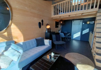 Knusse woonkamer in een Tiny House bij Bad Hoophuizen, Nederland, met loft en houten wandpanelen.
