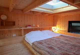 Camera da letto in legno con lucernario nella Tiny House di Bad Hoophuizen, Paesi Bassi, con letto grande.