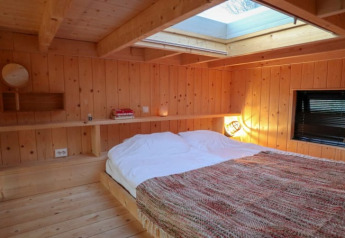 Hyggeligt soveværelse i træ med ovenlysvindue i Tiny House ved Bad Hoophuizen, Nederlandene.