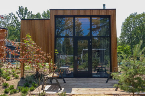 Modernes Tiny House Plus am Bad Hoophuizen in den Niederlanden, mit Holzverkleidung und großen Fenstern.