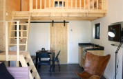Modern lodge interior with loft, wooden decor, stylish pendant light, small kitchen and cozy seating.