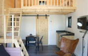 Interior de lodge moderno con altillo, decoración de madera, lámpara colgante y sala acogedora.