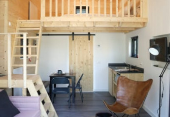 Moderne lodge med højt til loftet, hems, træinteriør, stilfuld belysning og åben opholdsstue.