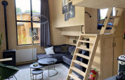 Modern tiny house at Bad Hoophuizen with loft bed, wooden interior, cozy sofa, and large window.