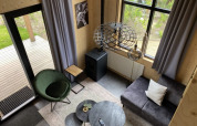 Vista de la sala en Tiny House en Bad Hoophuizen, Países Bajos, decorado moderno y ventanales grandes.